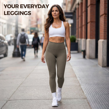 Woman walking down city street wearing olive green high-waisted everyday leggings and white sports bra